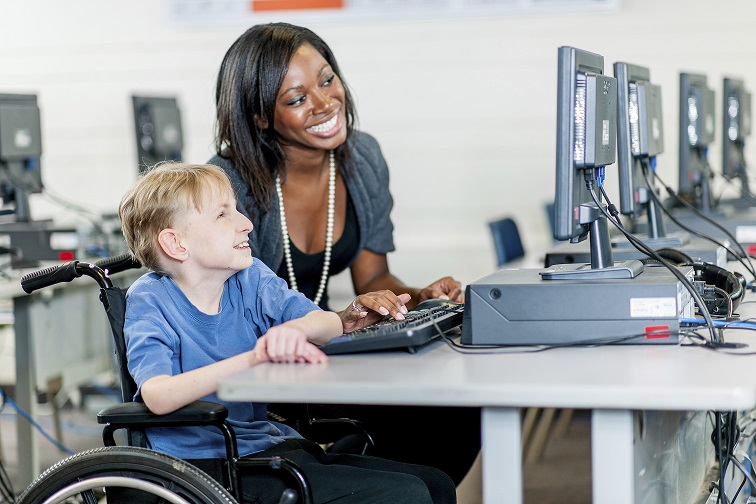 Image of a person sitting in a wheelchair in front of a computer